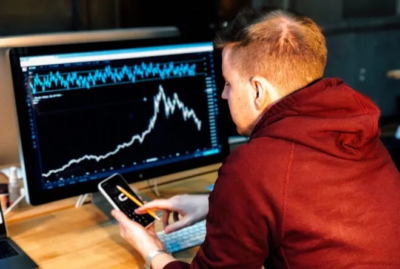 Analyst reviewing fuel price trends on a computer while holding a cellphone