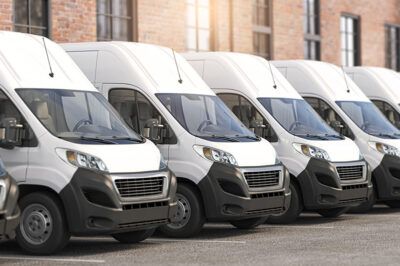 A lineup of white cargo vans representing a fleet