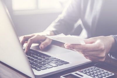 Business professional reviewing fuel card receipts on laptop