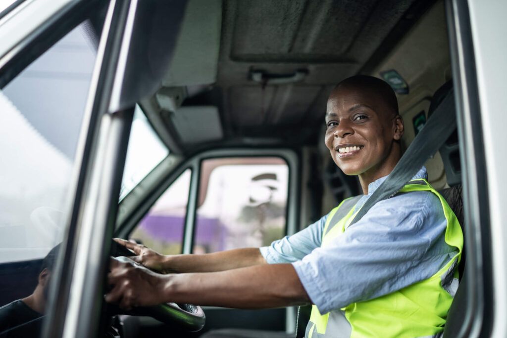 A fleet driver is in the cab of her truck, buckled up and ready to drive her route set up with telematics.
