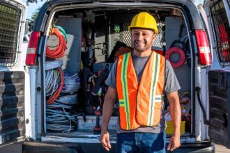 An electrician stands outside his open fleet van before heading into a job site.