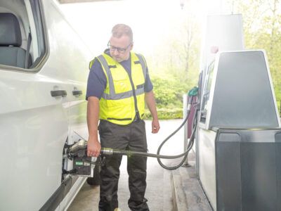 A fleet driver fuels his van at a gas station with his fleet fuel card.