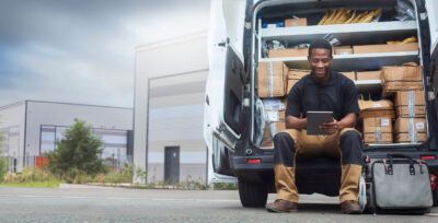 A fleet owner reviews fuel card analytics on a tablet outside near his fleet of trucks.
