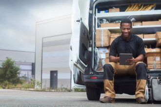A fleet owner reviews fuel card analytics on a tablet outside near his fleet of trucks.