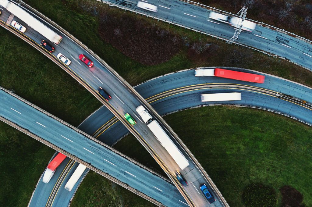 Aerial view of a highway clover leaf with fleet semi trucks driving their route.