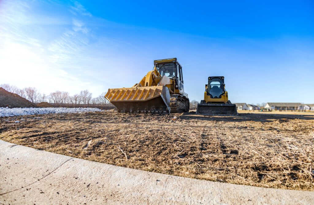 Construction vehicles on a worksite clearing land for building a home.