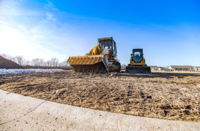 Construction vehicles on a worksite clearing land for building a home.