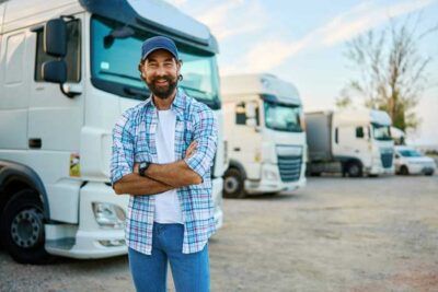 A fleet owner happily stands outside his fleet of vehicles.