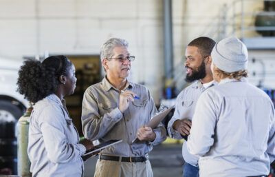 A team of drivers get instruction from their manager about new fleet fuel card program.