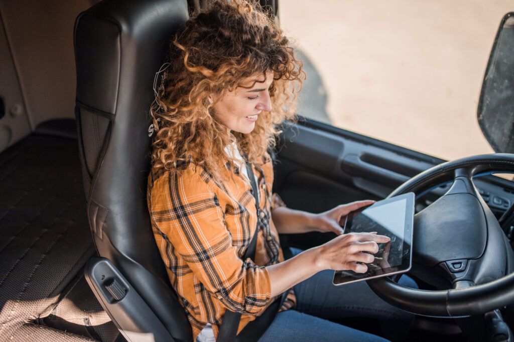A truck drivers uses her tablet from the cab of her semi to find fueling stations in her fleet card network before heading out on her route.